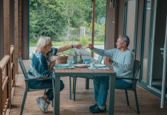 Deux personnes prennent le petit-déjeuner sur la terrasse de Tiny Wander Lodge à Holiday Park Sallandshoeve, Pays-Bas.