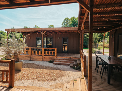 Vista exterior de Tiny Wander Lodge, con terraza de madera, área de estar y vegetación natural alrededor.