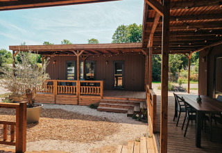 Vista exterior de Tiny Wander Lodge, con terraza de madera, área de estar y vegetación natural alrededor.