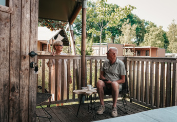 Couple senior prenant un café sur la terrasse d’une tente safari de luxe à Holiday Park Sallandshoeve.