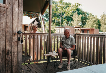 Couple senior prenant un café sur la terrasse d’une tente safari de luxe à Holiday Park Sallandshoeve.