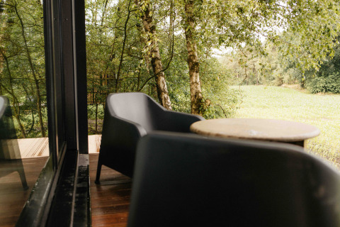 Terrasse med to sorte stole og et bord, udsigt til grøn skov ved Nokken NKN-18 Cabin, Wilsumer Berge.