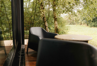 Terrasse med to sorte stole og et bord, udsigt til grøn skov ved Nokken NKN-18 Cabin, Wilsumer Berge.