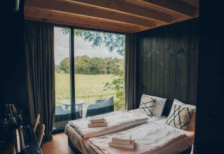 Minimalist bedroom at Nokken NKN-18 Cabin, Wilsumer Berge, Germany, featuring field and nature view.