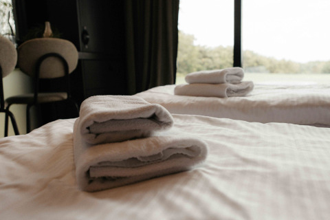 Folded towels rest on beds inside a cozy Nokken NKN-18 Cabin at Wilsumer Berge, Germany, with a scenic view.