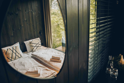 Reflectie van het gezellige Nokken NKN-18 Cabin slaapgedeelte bij Wilsumer Berge, Duitsland, door een raam.