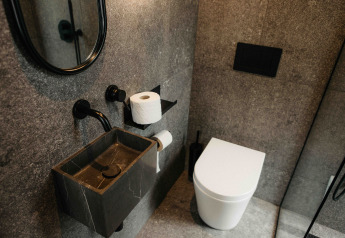 Salle de bain moderne dans la cabine Nokken NKN-18 Ă Wilsumer Berge, Allemagne, avec lavabo sombre et WC blanc.
