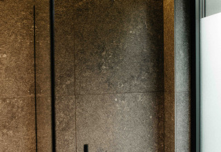 Modern shower with black fixtures and gray tiles in the Nokken NKN-18 Cabin at Wilsumer Berge, Germany.