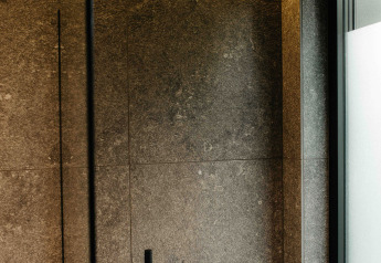 Douche moderne avec robinetterie noire et carreaux gris dans la Nokken NKN-18 Cabin à Wilsumer Berge, Allemagne.