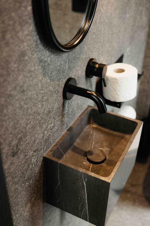 Moderne badeværelsesvask i sort sten med sort armatur og toiletrulleholder, Nokken NKN-18 Cabin, Tyskland.