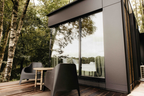 Terrazza esterna moderna con sedie nere e tavolo presso Nokken NKN-18 Cabin a Wilsumer Berge, Germania.