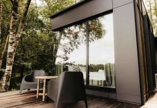Terrasse extérieure moderne avec fauteuils noirs et table à la Nokken NKN-18 Cabin à Wilsumer Berge, Allemagne.