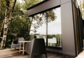 Terrazza esterna moderna con sedie nere e tavolo presso Nokken NKN-18 Cabin a Wilsumer Berge, Germania.