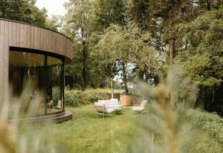Moderne ronde LumiPod tiny house met grote ramen en buiten hottub in het bos bij Wilsumer Berge, Duitsland.