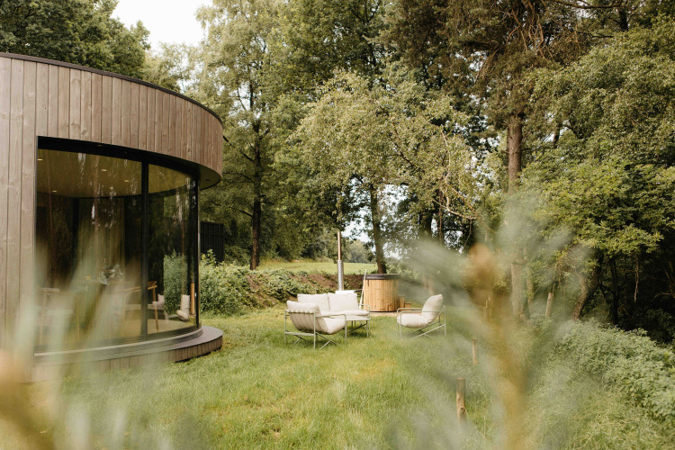 Moderne ronde LumiPod tiny house met grote ramen en buiten hottub in het bos bij Wilsumer Berge, Duitsland.