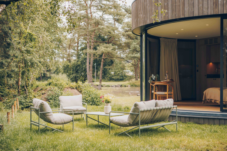 Outdoor seating area with modern lounge chairs outside LumiPod tiny house in Wilsumer Berge, Germany.