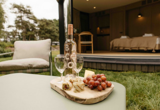 Buitentafel met wijn, glazen, kaas en druiven bij LumiPod tiny house op Wilsumer Berge in Duitsland.