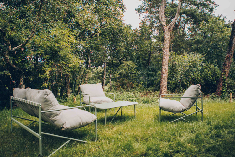 Buiten zithoek met comfortabele stoelen en tafel tussen bomen bij LumiPod met hottub op Wilsumer Berge, Duitsland.