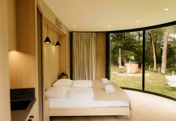 Chambre moderne dans un tiny house LumiPod à Wilsumer Berge, Allemagne, avec grandes baies et hot tub extérieur.