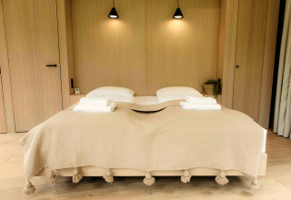 Schlafzimmer im LumiPod Tiny House bei Wilsumer Berge, Deutschland mit Doppelbett und heller Decke.