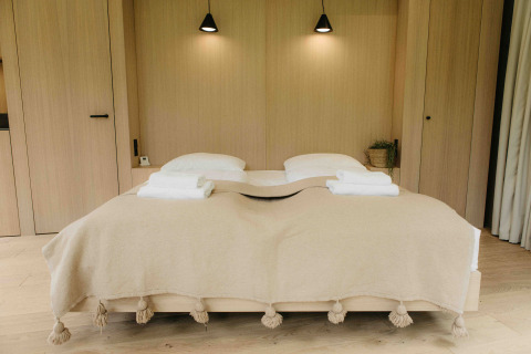 Slaapkamer in LumiPod tiny house bij Wilsumer Berge, Duitsland met tweepersoonsbed en beige deken.