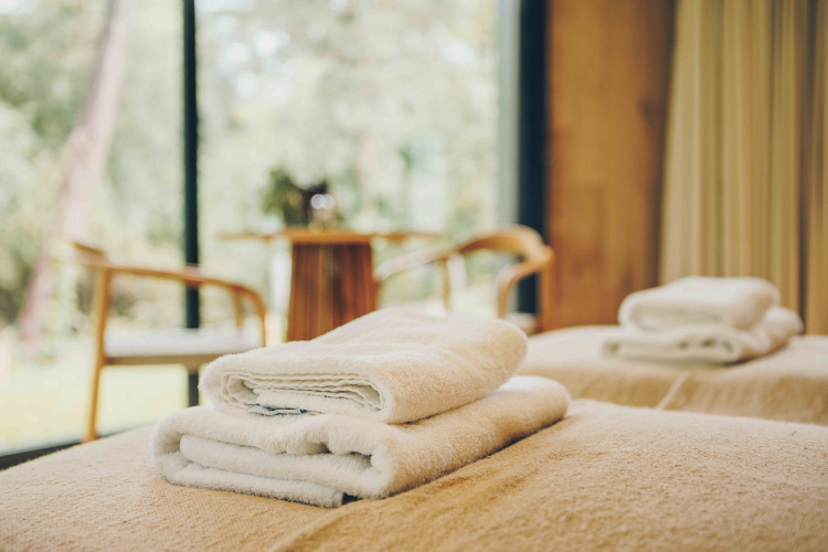 Luxurious folded towels on a bed inside LumiPod with hot tub at Wilsumer Berge, Germany.