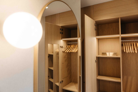 Open houten kledingkast met hangers in een LumiPod tiny house bij Wilsumer Berge, Duitsland, met moderne verlichting.