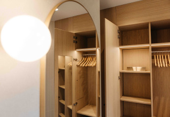 Guardaroba aperto in legno con appendiabiti in una tiny house LumiPod a Wilsumer Berge, Germania, con luce moderna.