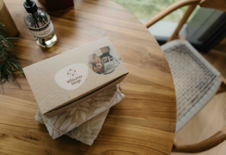 Een Wilsumer Berge welkomstdoos op een houten tafel in de LumiPod tiny house met handdoeken en zeep.