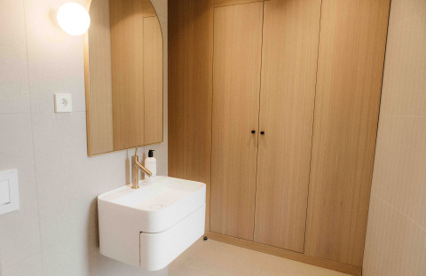 Modern kleine badkamer in LumiPod met wastafel, houten kasten en spiegel bij Wilsumer Berge, Duitsland.
