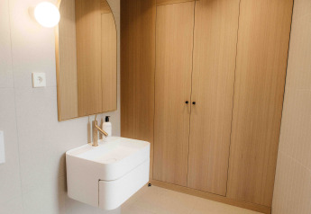 Bagno moderno di una tiny house LumiPod con lavabo, specchio e armadi di legno a Wilsumer Berge, Germania.