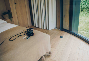 Interno accogliente di una tiny house LumiPod a Wilsumer Berge, Germania, con Polaroid sul letto.