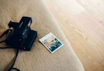 Appareil photo Polaroid et photo instantanée sur un canapé beige dans une tiny house LumiPod avec jacuzzi à Wilsumer Berge, Allemagne.