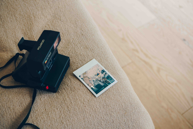 Polaroidcamera en foto op een beige bank in LumiPod tiny house met hottub in Wilsumer Berge, Duitsland.