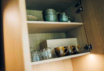 Placard en bois dans une tiny house à Wilsumer Berge, Allemagne, avec bols, tasses et verres en céramique.