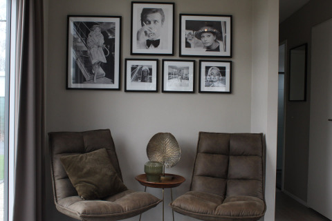 Deux fauteuils confortables et une petite table avec décoration, encadrés par des photos noir et blanc au mur.