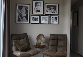 Deux fauteuils confortables et une petite table avec décoration, encadrés par des photos noir et blanc au mur.