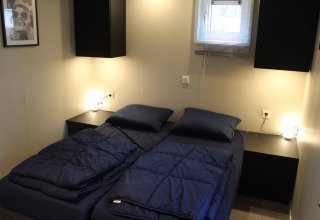 Chambre moderne avec deux lits simples, literie bleu foncé et tables de nuit à Just Nature 4, Beekbergen.