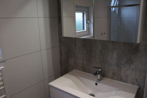 Lavabo de salle de bain moderne avec grand miroir et fenêtre au lodge Just Nature 4 à Beekbergen, Pays-Bas.