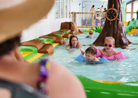 Kinder spielen mit Erwachsenen im Indoor-Pool im Familievakantiepark Krieghuusbelten, Overijssel.