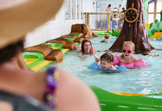 Children and parents enjoy playing together in an indoor pool at Familievakantiepark Krieghuusbelten.