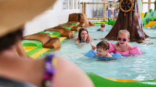 Des enfants et des parents s’amusent dans la piscine intérieure du Familievakantiepark Krieghuusbelten.