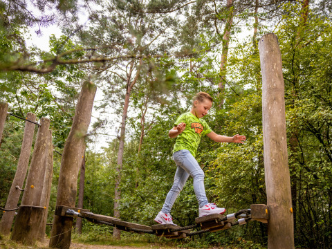 Kind balanceert op een avonturenparcours bij Familievakantiepark Krieghuusbelten in Overijssel, Nederland.
