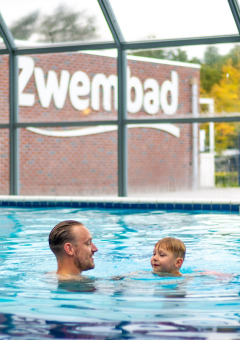 Un homme et un enfant nagent dans la piscine intérieure du Familievakantiepark Krieghuusbelten à Overijssel, Pays-Bas.