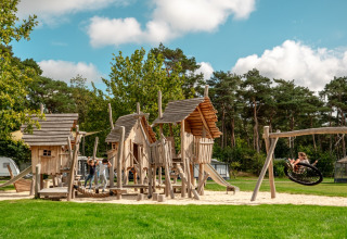 Niños jugando en un parque infantil de madera con columpios en Familievakantiepark Krieghuusbelten, Overijssel, Países Bajos.