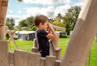 Dreng leger på legeplads med kikkert i Familievakantiepark Krieghuusbelten, Overijssel, Holland.
