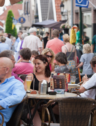 Des personnes profitent d’une journée animée à une terrasse de café à Raalte, Overijssel, aux Pays-Bas, entourées de visiteurs.