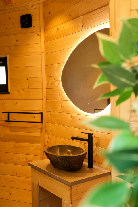 Moderno baño en Wellnest de Camping Vinkenhof, Países Bajos, con madera y lavabo de piedra.
