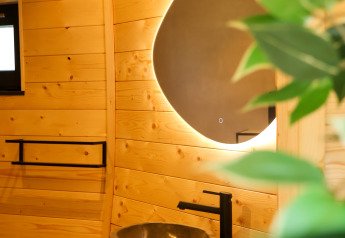 Bagno moderno al Wellnest, Camping Vinkenhof, Paesi Bassi, con legno e lavabo in pietra.