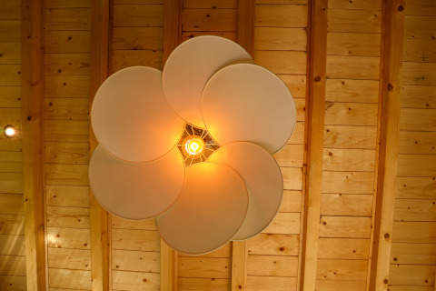 Lámpara de techo moderna con diseño en forma de pétalos iluminando cálidamente, vista desde abajo en Wellnest.